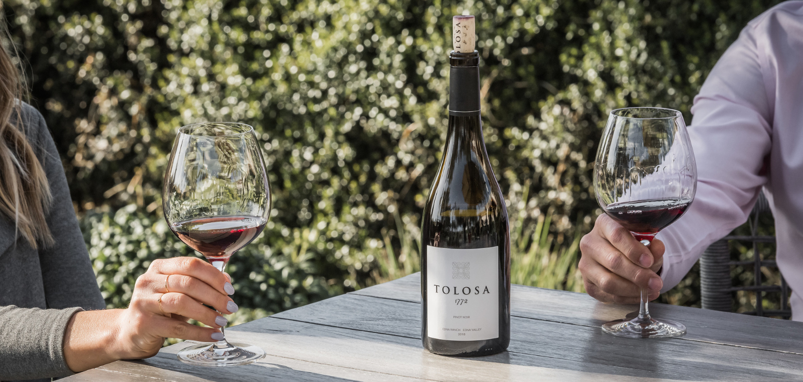 Image of two people drinking wine with a wine bottle at the table