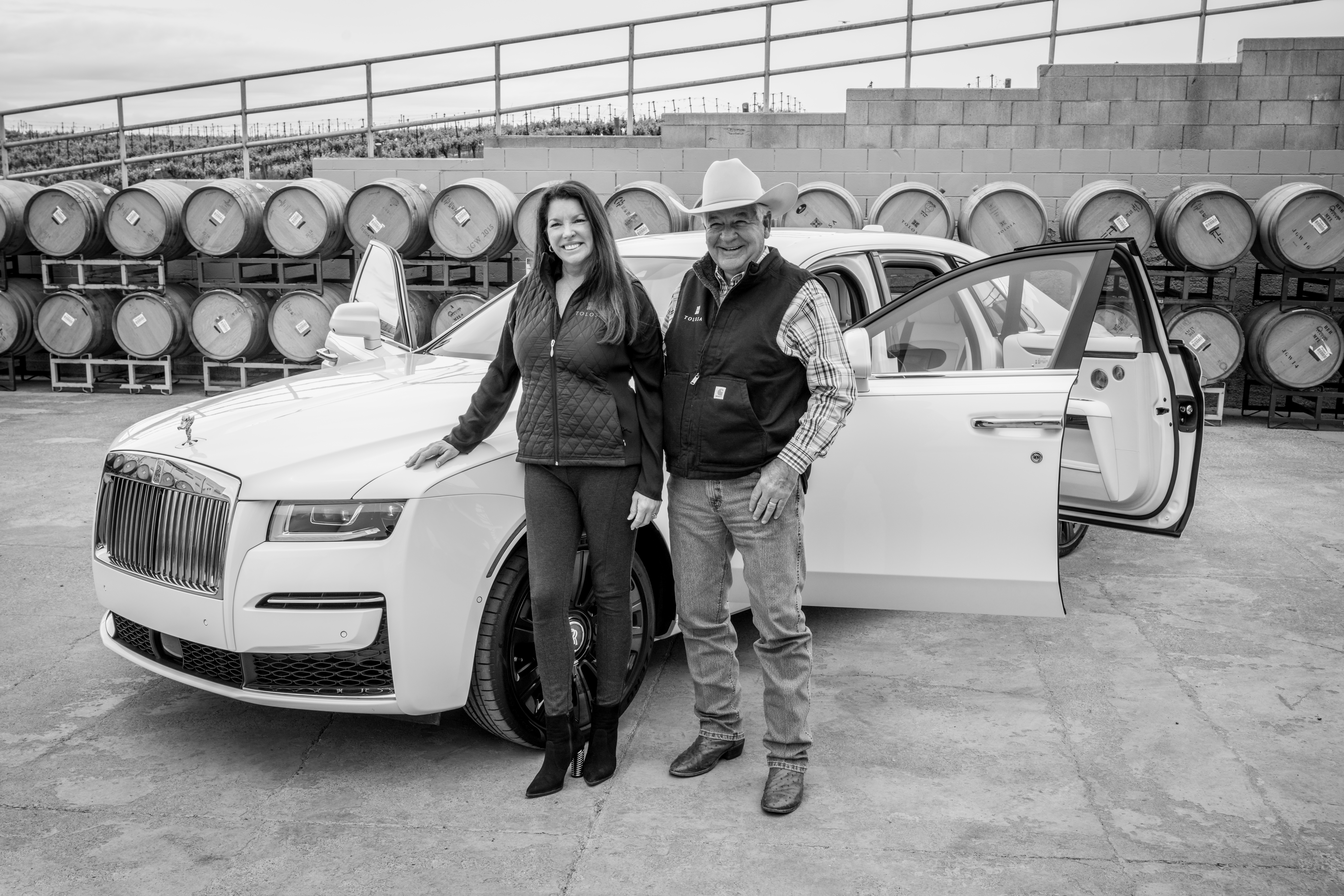 Black and white photo of Vintner Robin Baggett and his wife, Michelle Baggett, in front of a white Rolls Royce